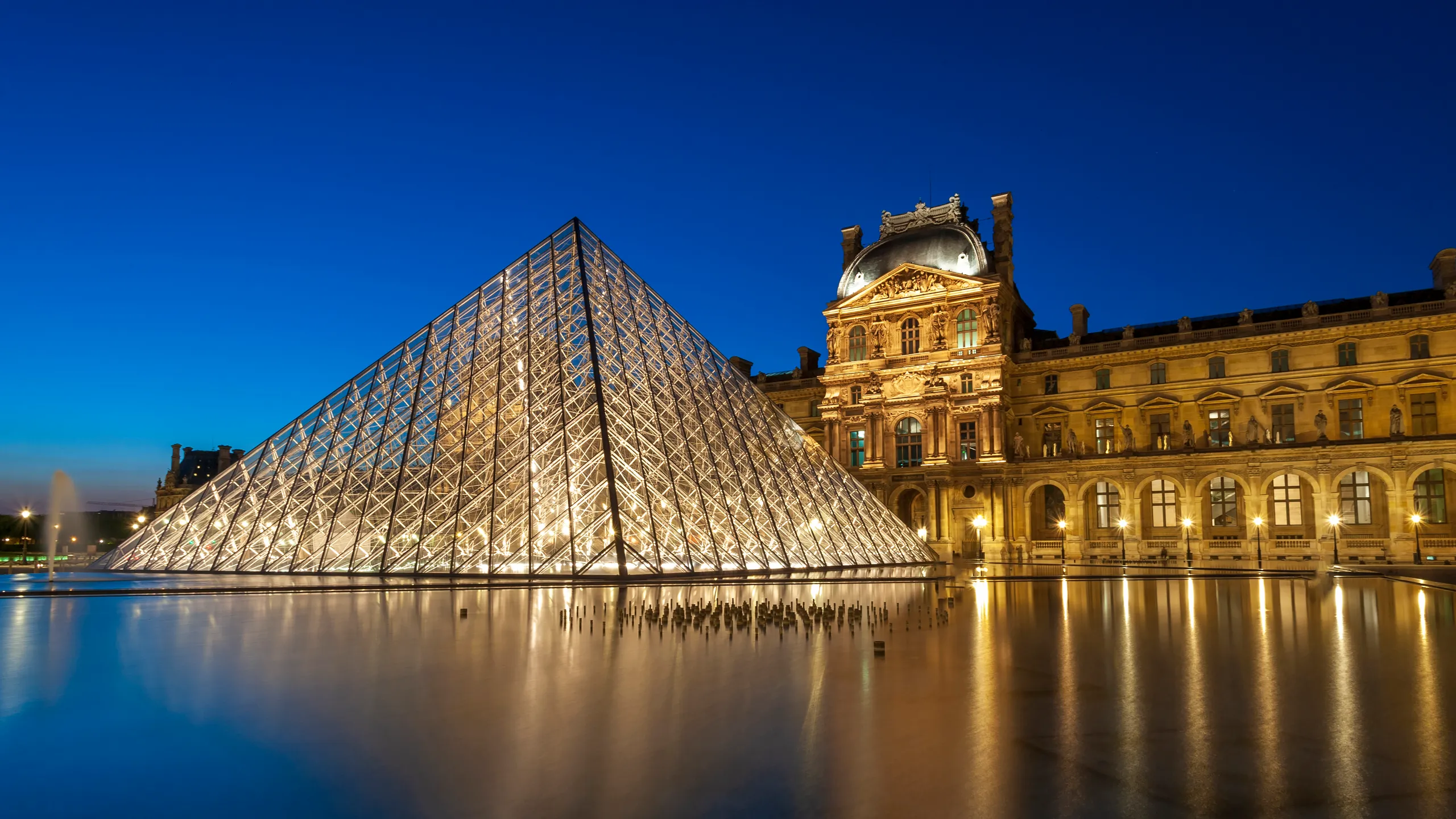 Vue nocturne du Musée du Louvre et de sa pyramide en verre avec le texte 'LA DÉFENSE PÉNALE SUR MESURE' affiché en surimpression, symbolisant un service juridique personnalisé.